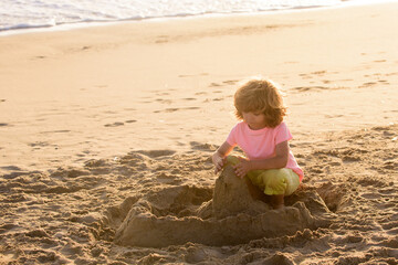 Child play with sand on summer beach. Kid build sandcastle. Kids summer vacation.