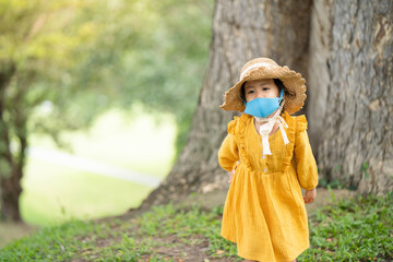 Cute little girl with protective face mask walking at park.