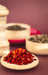 dried red chilli or paprika flakes on wooden plate close up