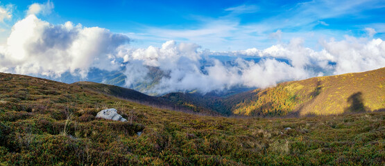 Autumn mountain landscape. White clouds are flying along the ridge.