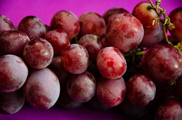a bunch of red grapes on a purple background