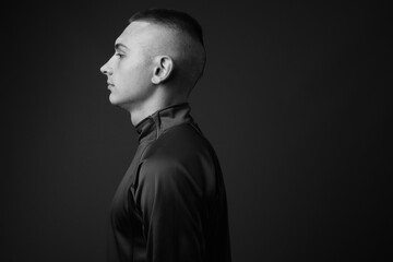 Studio shot of young handsome man with short hair against gray background