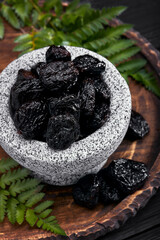 Fresh prunes in stone bowl. Prunes on stone dark table. Prunes healthy food. Dried plums in bowl.