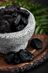 Fresh prunes in stone bowl. Prunes on stone dark table. Prunes healthy food. Dried plums in bowl.
