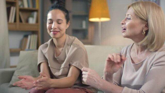 Medium shot of joyful multi ethnic women discussing financial issues learning about financial literacy and basics of accounting doing paperwork together