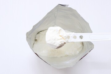 Baby powder milk formula in the package with a spoon.  Infant formula in spoon and package on white background