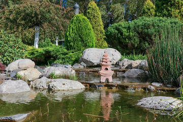 Pond with decorative stone figurine and landscaping in Asian style