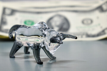 Glass figurine of a bull on a background of US dollars. Concept: business, stock exchange, finance,...