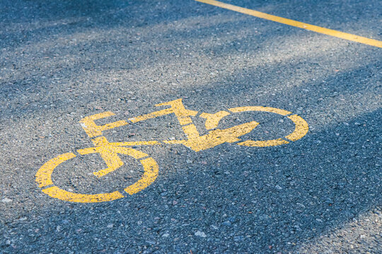 Road sign painted with yellow paint on the asphalt on the bike path
