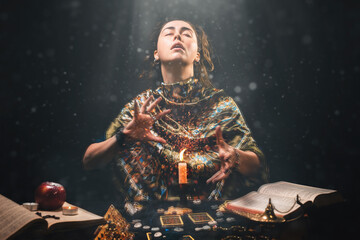 Astrology, magic and divination. The sorceress creates the magic of divination over a candle. Black background. There are magic items on the table - obrazy, fototapety, plakaty
