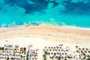 Beach vacation and travel background. Aerial drone view of beautiful atlantic tropical beach with straw umbrellas, palms and boats. Bavaro beach, Punta Cana, Dominican Republic.