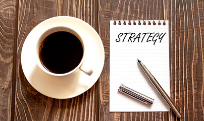 STRATEGY - white paper with pen and coffee on wooden background