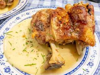 Pork knuckle on a bed of mashed potatoes puree decorated with green chives. Traditional german oktoberfest dish