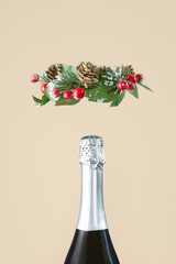 Neck of a champagne bottle with silver foil and a Christmas wreath close-up. The concept of a celebration, holiday, new year. Minimalism, copy space.