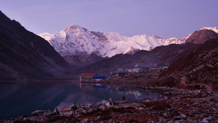Beautiful view of small Sherpa village Gokyo, Sagarmatha National Park, Nepal in the evening with lights reflected in water of the lake and majestic mountain Cho Oyu (summit 8,188 m) in background.