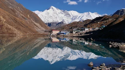 Papier Peint photo Cho Oyu Vue imprenable sur le village de Sherpa Gokyo, le parc national de Sagarmatha, l& 39 Himalaya, le Népal et la majestueuse montagne enneigée Cho Oyu (8 188 m) reflétée dans l& 39 eau paisible du lac clair de Gokyo.