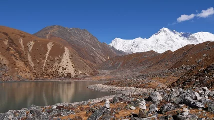 Papier Peint photo autocollant Cho Oyu Champ rocheux escarpé au bord du lac Second sur le trek des trois cols dans la vallée de Gokyo, région de Khumbu, Himalaya, Népal avec la majestueuse montagne glaciaire Cho Oyu (sommet 8 188 m) en arrière-plan.