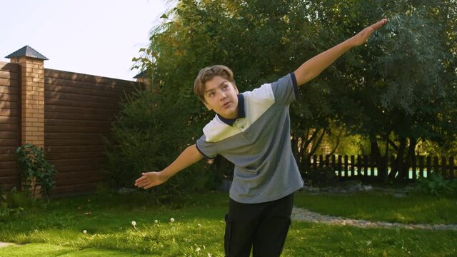 A young, Caucasian, handsome teenage boy with outstretched arms depicts an airplane. Positive emotions, non-verbal gestures. Everyday leisure