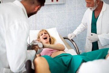 In the hospital woman in labor pushes to give birth, obstetricians assisting
