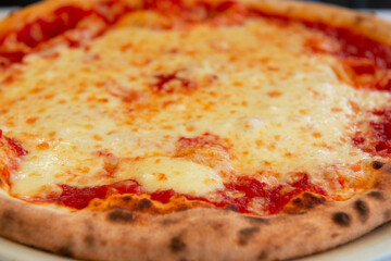 Delicious tasty traditional italian pizza Margarita - mozzarella cheese, tomatoes and crispy dough cooked in the oven in restaurant or pizzeria, detail, soft focus
