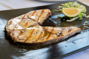 Cooked swordfish. Grilled slice of fish with lemon and salsd on plate in restaurant