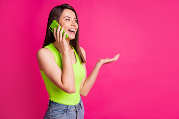 Portrait of brunette hair girl talk mobile cellphone surprised happy news look empty space isolated over pink color background