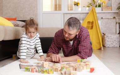 happy father playing with his daughters lying on the floor. Family games with children during the pandemic