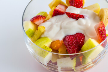 Fruit salad with natural yogurt in glass bowl isolated on white