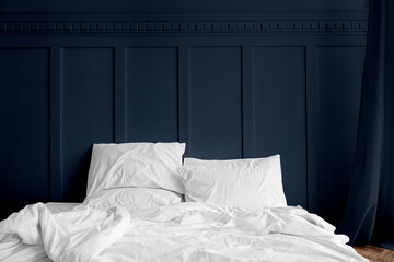 White bed linen on a mattress in a midnight blue bedroom - obrazy, fototapety, plakaty