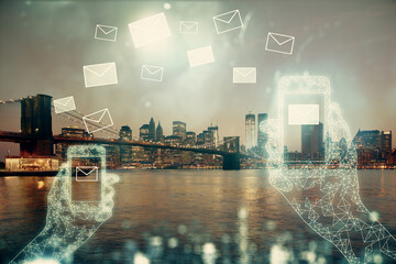 Double exposure of envelop hologram flying from gadget and city view background. Concept e-mail.