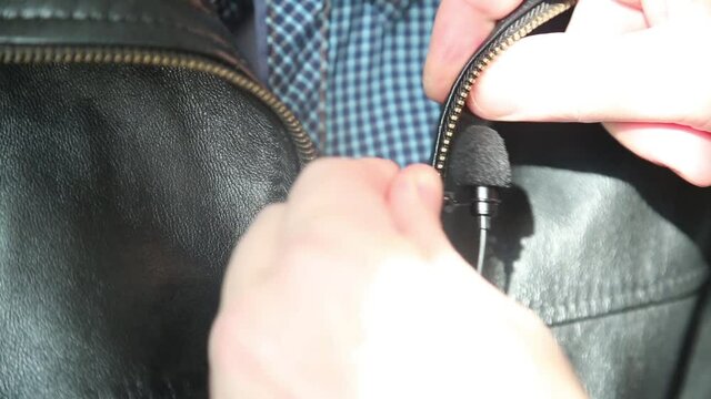Correspondent installs a lavalier microphone on a leather jacket