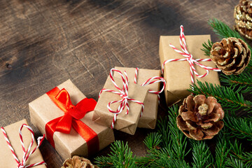 Gift boxes in craft paper. Christmas background. Christmas gifts under spruce branches on a brown wooden background. Christmas Flatly. Сopyspace	