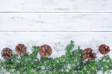 christmas background with pine cones, fir branches and snowflakes on white wooden boards