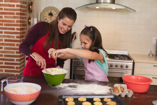 Caucasian woman with her daughter baking in a kitchen and wearing apron