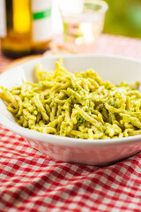 Detail shot of dinner table with a bowl of pasta pesto genovese, blurred background. Selective focus - shallow depth of field.