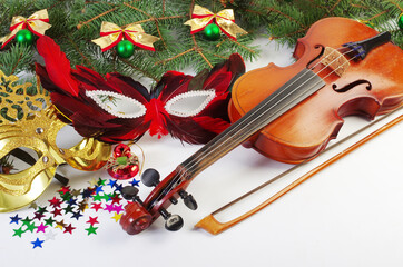 Violin, bow, carnival masks and Christmas decorations on a Christmas tree branch.