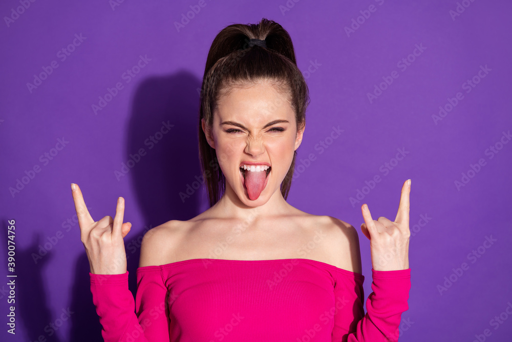 Sticker Photo of crazy young girl raise two arms show horns stick out tongue wear pink uncovered shoulders top isolated violet color background