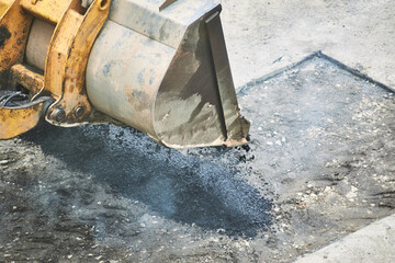 tractor unloading hot asphalt into the pit. road repair