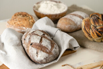 Fresh loaves of bread with wheat and grain on a white wooden table