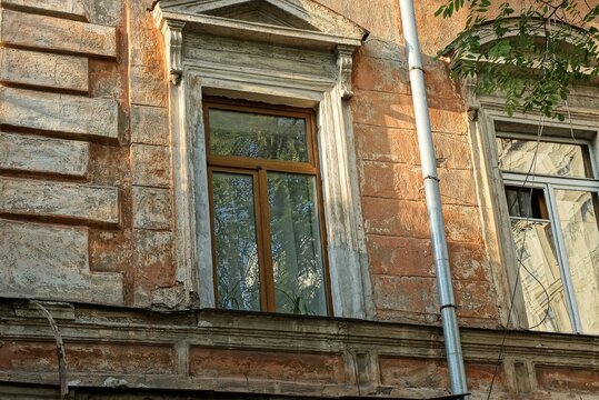 one window on an old shabby brown stone wall outside