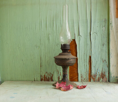 an old kerosene lamp and a bouquet of lupines lie on an old brown porch