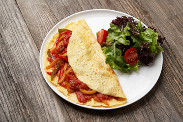 Omelette with vegetables on wooden background