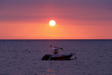 Fototapeta premium Sunset over indian ocean, Madagascar Nosy be beach with boat silhouette. Travel Africa for vacation concept.