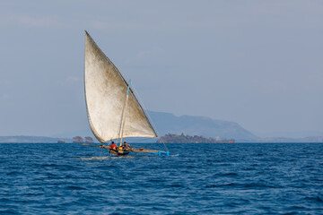 Malagasy fisher man on sea in traditional handmade dugout wooden sailing boat. Everyday life on...