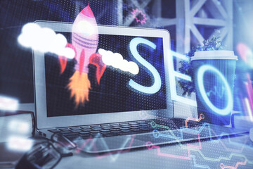 Double exposure of table with computer and seo drawing hologram. Search optimization concept.