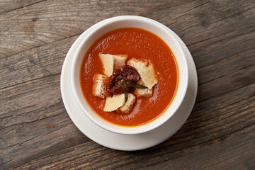Bowl of tomato soup with cheese and bread.