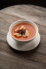 Bowl of tomato soup with cheese and bread.