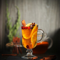 mulled wine tea with cinnamon and orange stands on a dark background	
