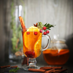 mulled wine tea with cinnamon and orange stands on a dark background	
