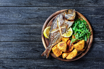 Whole roasted dorado fish with potato, top view